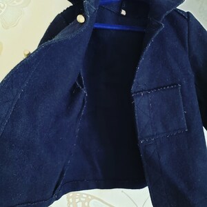 May include: A black hooded jacket with a small pocket on the right side. The jacket is unbuttoned and the inside is visible.
