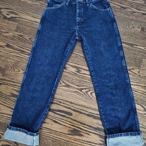 May include: A pair of dark blue denim jeans with a button fly and cuffed hems.