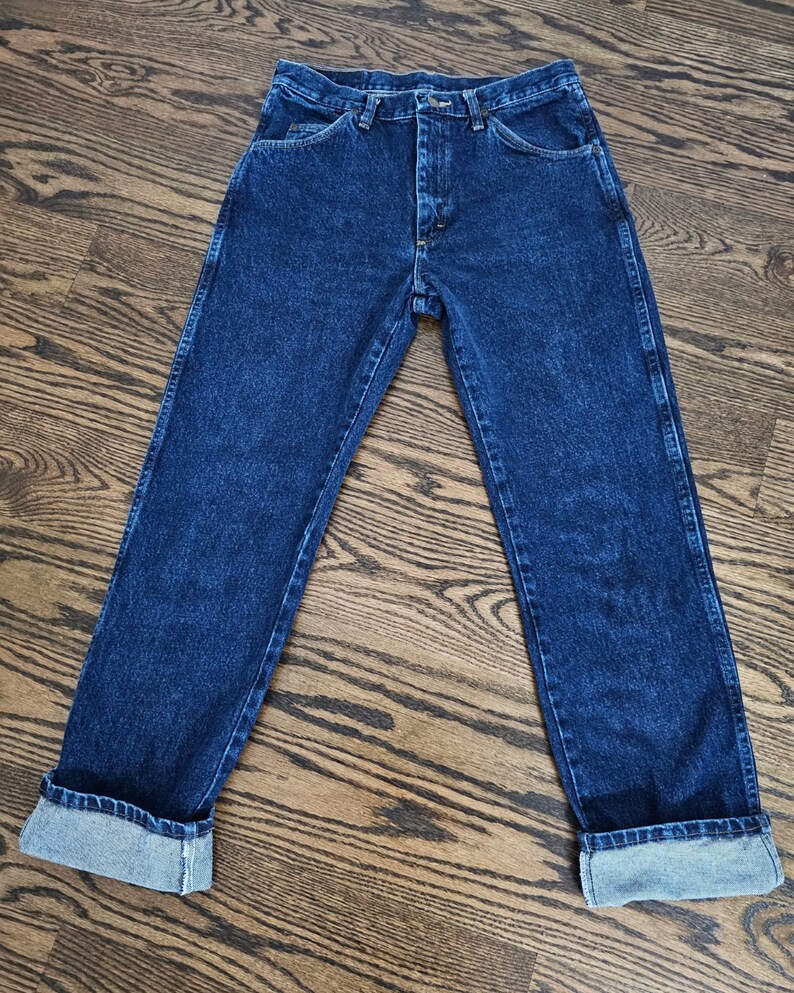 May include: A pair of dark blue denim jeans with a button fly and cuffed hems.