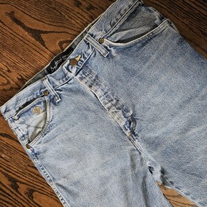 May include: Light blue denim jeans with a classic five-pocket design. The jeans feature a button and zipper closure, belt loops, and rivets. The jeans are made of a durable denim fabric and have a faded wash.