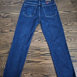 May include: A pair of dark blue denim jeans with a Wrangler logo on the back pocket.