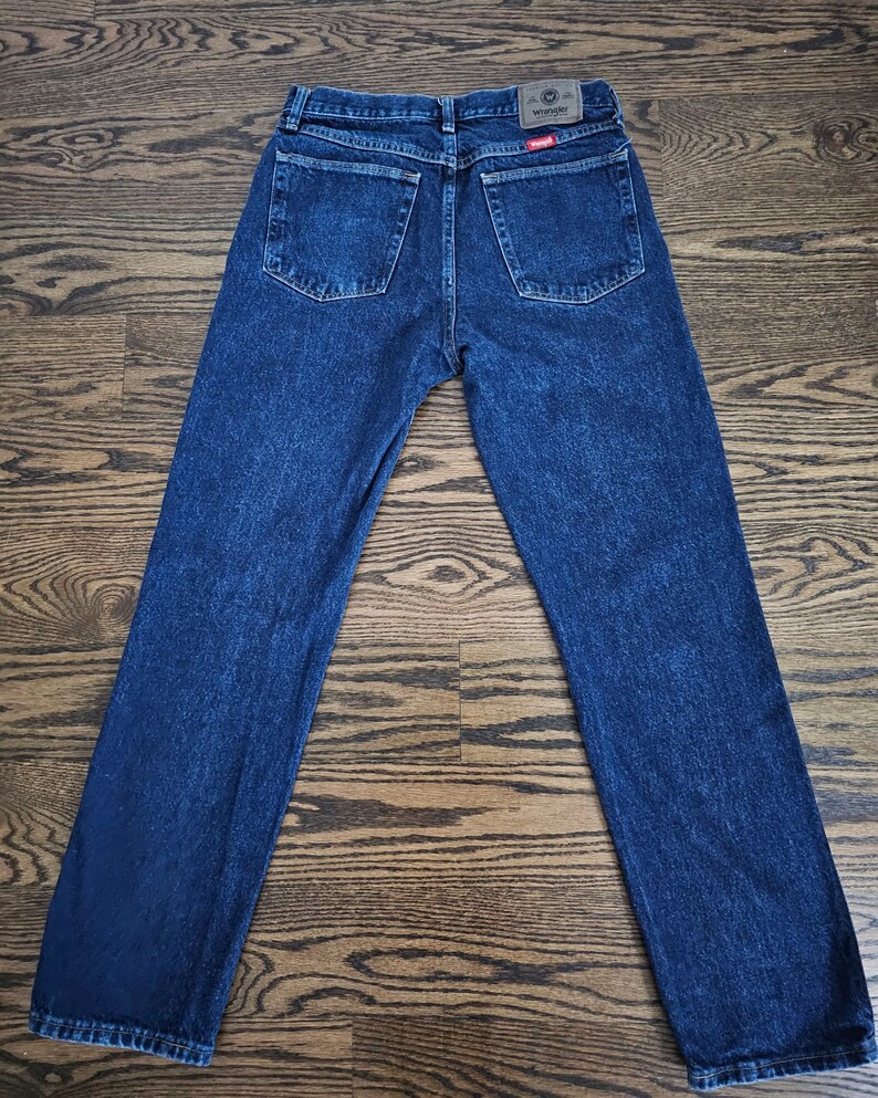 May include: A pair of dark blue denim jeans with a Wrangler logo on the back pocket.