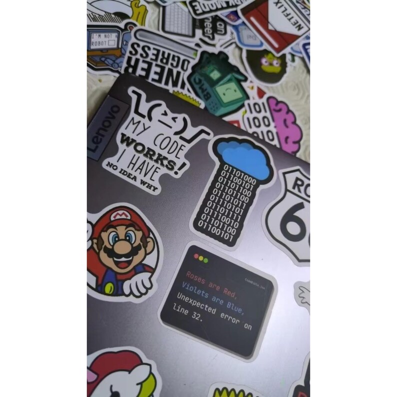 K&ouml;nnte beinhalten: Ein Laptop, der mit verschiedenen Aufklebern bedeckt ist. Zu den Aufklebern geh&ouml;ren eine Mario-Figur, Bin&auml;rcode und der Text "My code works! I have no idea why." Weitere Aufkleber enthalten den Text "Roses are Red, Violets are Blue, Unexpected error on line 32."