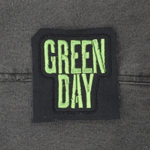 Può includere: Toppa con logo della band Green Day con tessuto nero e lettering ricamato verde.
