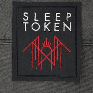 Op de afbeelding: Zwarte en witte geborduurde patch met de tekst "SLEEP TOKEN" in wit en een rood gestileerd logo.