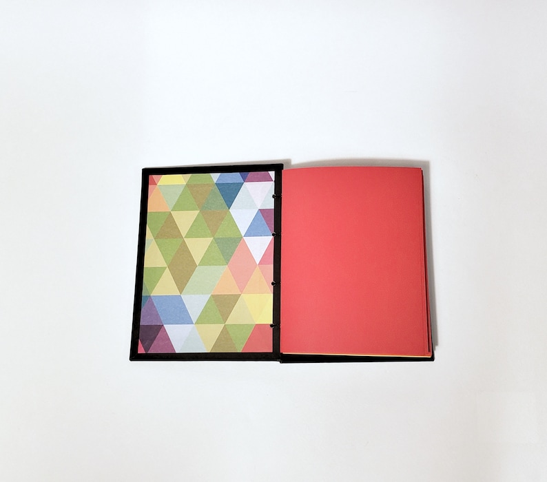 May include: A closed notebook with a black cover. The front cover has a geometric pattern of colorful triangles. The back cover is solid red.