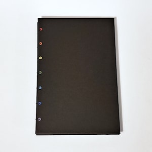May include: A black notebook with a rainbow of colored stitching along the spine.