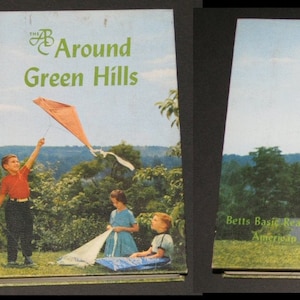 May include: The cover of a children's book titled "The A B Around Green Hills" with a green spine. The cover features three children playing with kites in a field.