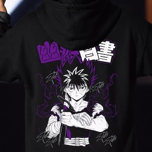 Pode incluir: Um moletom com capuz preto com uma estampa gráfica nas costas. O design exibe um personagem de anime com cabelo preto espetado, segurando uma espada, cercado por efeitos de energia roxos e texto japonês em blocos brancos e roxos.