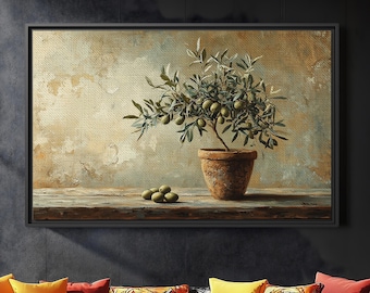 May include: A framed painting of an olive tree in a terracotta pot, set on a wooden surface. The painting hangs above a black leather sofa with colorful throw pillows. A black ottoman sits in front of the sofa.