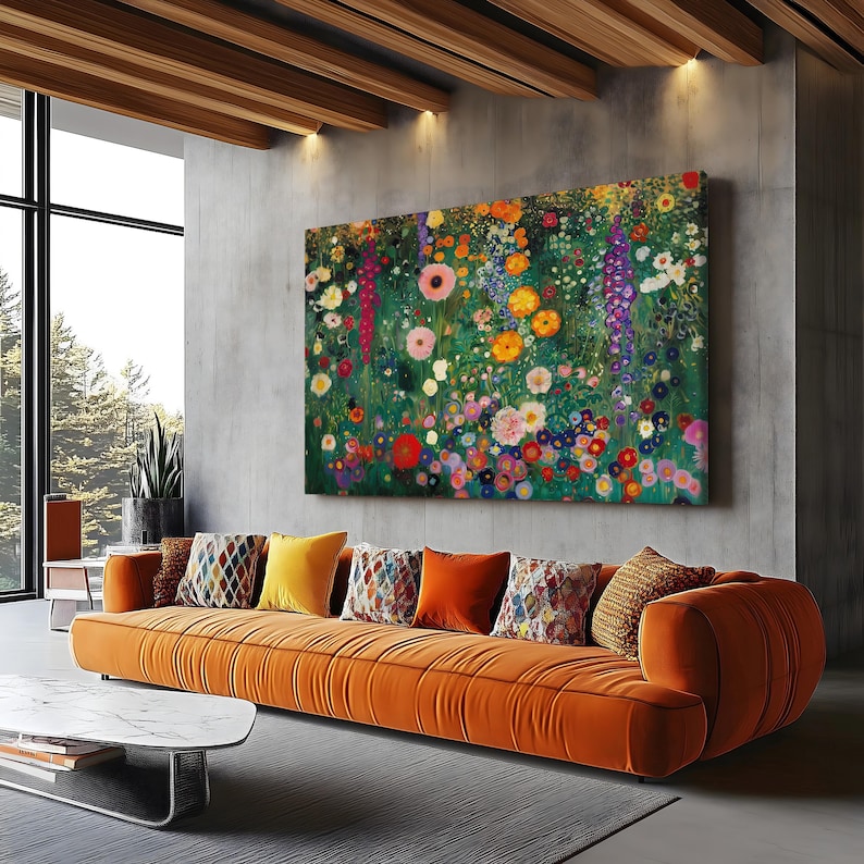 May include: A large floral painting with a vibrant array of colorful flowers, including pink, yellow, and red blooms, hangs above an orange sofa. The room features a modern design with a concrete wall and wooden ceiling beams.