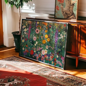 May include: A framed floral art print featuring a vibrant meadow of colorful flowers in shades of pink, yellow, purple, and white. The artwork is displayed on a wooden floor, leaning against a wall, with a potted plant and a vintage cabinet in the background.
