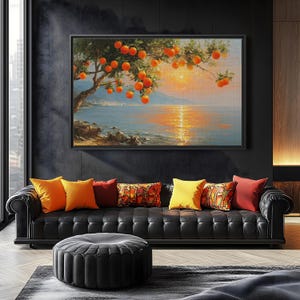 May include: A framed painting of an orange tree with ripe fruit hanging over a body of water at sunset. The painting hangs above a black leather sofa with colorful throw pillows and a black ottoman. The room has dark walls.