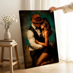 May include: A canvas print depicts a romantic couple embracing. The man wears a brown fedora, a white shirt, a black vest, and a bow tie. The woman is in a black dress. The background is a mix of teal and brown.