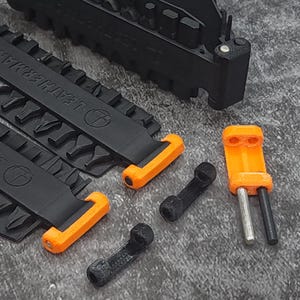 May include: Two black multi-tool keychains with orange handles and a small orange and silver fire starter. The keychains have the text "Leatherman" printed on them.