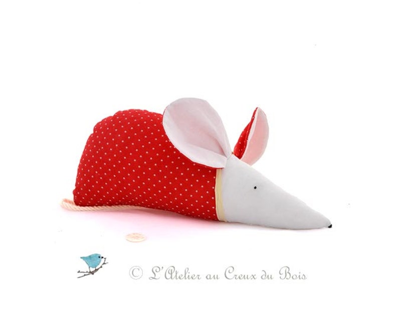 May include: A red and white stuffed mouse with white polka dots on the red fabric. The mouse has a long white snout and pink ears.