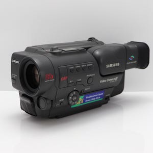 Peut inclure: Caméscope Samsung noir avec objectif, boutons et poignée. L'appareil photo dispose d'un zoom numérique 22x et d'un écran d'affichage. Le texte "Video Camera 88" est visible sur le côté.