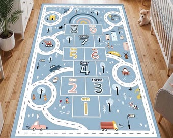 May include: A light blue children's play rug with a hopscotch grid and a road design, featuring numbers, cars, and illustrations. The rug has a white border and is designed for indoor use. The numbers are in a large font.