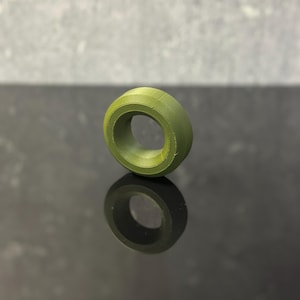 Könnte beinhalten: Ein grüner Gummiring mit einer glatten Oberfläche und einem runden Loch in der Mitte.