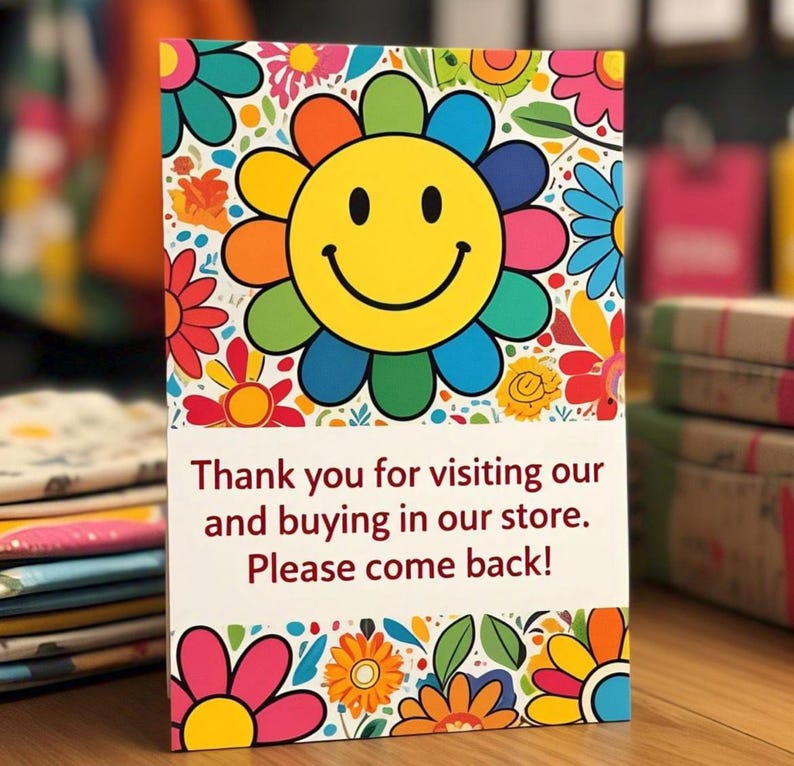 Puede incluir: Una tarjeta de agradecimiento rectangular con una cara sonriente amarilla grande rodeada de p&eacute;talos de flores coloridos. La secci&oacute;n inferior tiene un fondo blanco con el texto: Thank you for visiting our and buying in our store. Please come back!