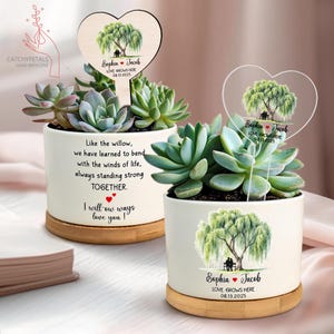May include: Two white ceramic planters with succulents, each featuring a heart-shaped sign with a willow tree illustration and the names "Sophia & Jacob." One sign is wood, the other clear. Text on the planters reads "Love Grows Here."