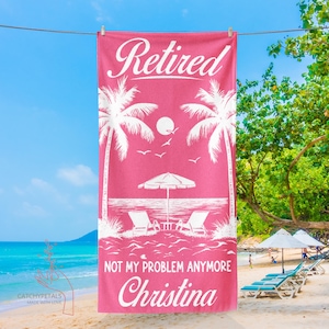 May include: A pink beach towel with the word "Retired" in white script. The towel features a beach scene with palm trees, a sun, and the text "NOT MY PROBLEM ANYMORE Christina". The towel is hanging on a clothesline at the beach.