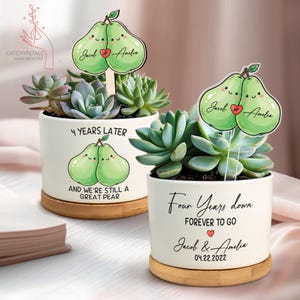 May include: Two white ceramic succulent planters with bamboo saucers. Each planter features a pear graphic and text. One reads "4 Years Later" and "And We're Still a Great Pear." The other reads "Four Years Down" and "Forever to Go."