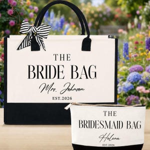 May include: A cream and black canvas tote bag with a black and white striped bow, featuring the text THE BRIDE BAG, Mrs. Johnson, and EST.2026, alongside a matching smaller pouch with the text THE BRIDESMAID BAG, Helena, and EST.2026.