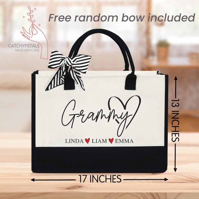 May include: A black and white tote bag with the word "Grammy" in script and the names Linda, Liam, and Emma. The bag is 17 inches wide and 13 inches tall. A striped bow is attached to the handle. The text "Free random bow included" is also visible.