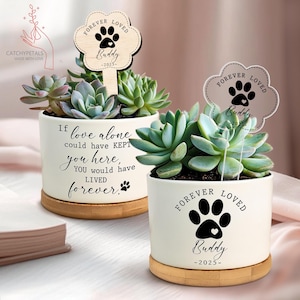 May include: Two white ceramic succulent planters with wooden bases. Each planter has a succulent plant and a wooden sign that reads "Forever Loved Buddy -2025-". One planter has the text "If love alone could have kept you here, you would have lived forever."
