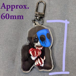 May include: A clear acrylic keychain featuring a character with a blue mask, black hood, and holding a bloody heart. The keychain is approximately 2.36 inches (60mm) in height and includes a metal clasp.