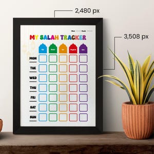 Könnte beinhalten: Ein gerahmter Druck mit schwarzem Rahmen, betitelt "My Salah Tracker". Der Druck zeigt einen farbenfrohen Wochen- und Monatsplan für Gebetszeiten, mit den Wochentagen vertikal und den Gebetszeiten horizontal. Rechts ist eine Topfpflanze.