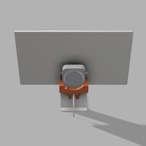 May include: A computer monitor with a gray screen is mounted on a stand. The stand has an orange bracket and a silver base. A gray speaker is attached to the back of the monitor.