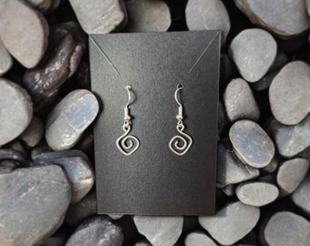 May include: A pair of silver dangle earrings with a spiral design. The earrings are on a black background.