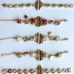 May include: Gold-toned watch bands with various decorative elements. Designs include bands with green stones, red floral accents, white flowers, pearls, and other embellishments. Each band features a gold clasp and chain.