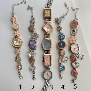 May include: Five decorative women's watch bracelets with various watch faces and embellishments. Styles include square, oval, and round faces, with decorative charms and chains. Each bracelet has a unique design with floral and heart accents.