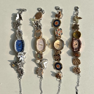 May include: Four charm bracelets with watches. Each bracelet has a different color scheme and features various charms, including butterflies, stars, hearts, and shells.