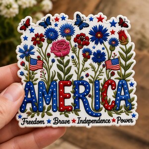 May include: A die-cut sticker featuring the word AMERICA in blue and red letters with white polka dots. The design includes illustrations of blue and red flowers, butterflies, and two small American flags. The text Freedom, Brave, Independence, Power is printed at the bottom with small stars.