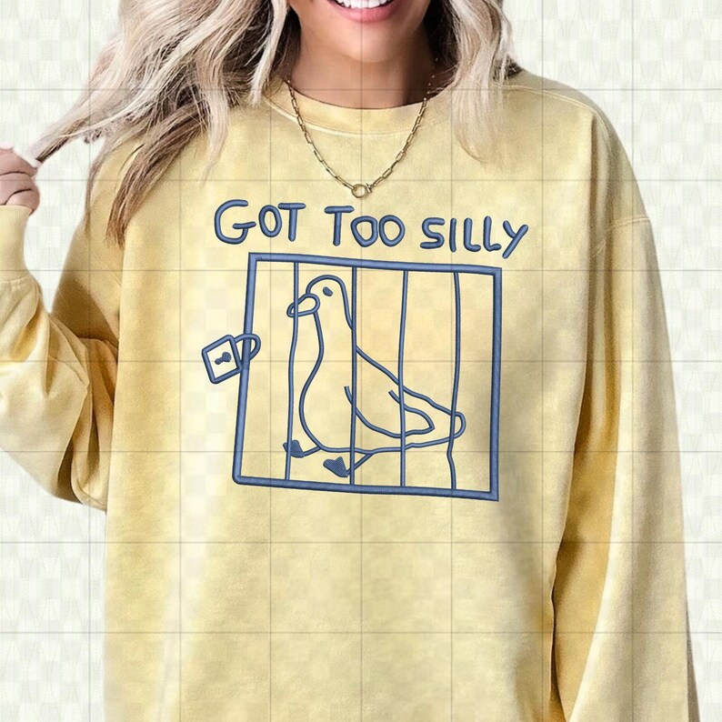 May include: Yellow sweatshirt with the text "GOT TOO SILLY" in blue. A blue outline of a bird in a cage is printed below the text. The sweatshirt has long sleeves and a crew neck.