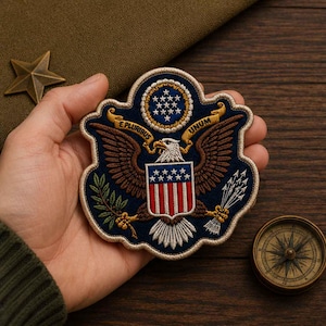 May include: A circular embroidered patch featuring a bald eagle with wings spread, holding an olive branch and arrows. The eagle displays a shield with red and white stripes and stars, topped by a circle of stars and the text E PLURIBUS UNUM.