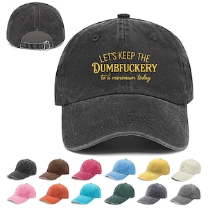 May include: A black baseball cap with the text "LET'S KEEP THE DUMBFUCKERY to a minimum today" in yellow. The cap has a curved brim and an adjustable strap. Several other colored caps are displayed below.