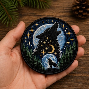 Puede incluir: Un parche bordado circular que muestra la silueta de un lobo negro aullando a la luna, rodeado por un cielo estrellado, una luna creciente, un lobo más pequeño sobre una colina y un denso bosque de pinos verdes con un borde negro.