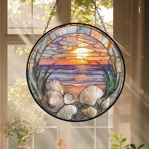 May include: A circular stained glass window showing a beach scene with seashells, ocean waves, and a sunset. The window is framed in black and suspended by a chain. The colours include shades of orange, purple, blue, and green.