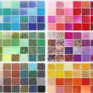 May include: A collection of small, colorful beads arranged in a grid of compartments. The beads are in various shades of blue, green, pink, red, purple, brown, yellow, and orange. Ideal for crafting and jewelry making.