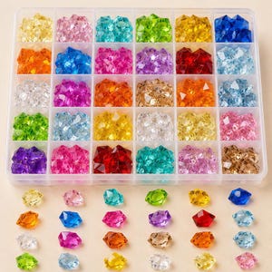 May include: A clear plastic storage container with thirty compartments, each filled with faceted, multi-colored acrylic gems in shades of red, blue, green, yellow, pink, purple, orange, and clear. Loose gems are arranged in rows below the box.
