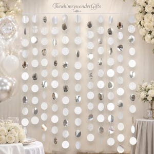 May include: A silver circular garland backdrop featuring multiple vertical strands of reflective and glittery discs. The text ThewhimsywonderGifts is printed at the top center. The garland consists of alternating shiny metallic and textured silver circles.