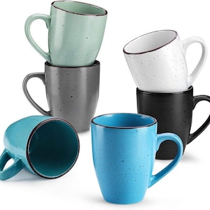 May include: A collection of ceramic mugs in various colors, including teal, light blue, gray, black, and white. Each mug has a speckled design and a contrasting rim. The mugs are stacked and arranged to showcase their design and color variations.