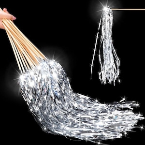 May include: A bundle of silver metallic fringe attached to multiple wooden dowels. The fringe is long and flowing, with a shiny, reflective surface. The image is set against a black background, highlighting the bright, shimmering effect of the fringe.