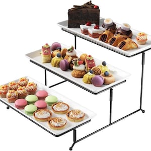 May include: A three-tiered serving stand with an assortment of pastries. The top tier holds a slice of chocolate cake and various desserts. The middle tier features colorful macarons and mini cakes. The bottom tier displays tarts and cupcakes.