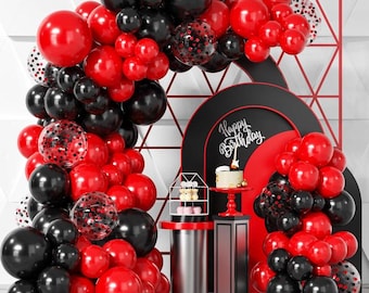 May include: A festive birthday party scene with a balloon arch in red, black, and confetti-filled clear balloons. A cake with a lit candle sits on a red stand, with the words "Happy Birthday" displayed.